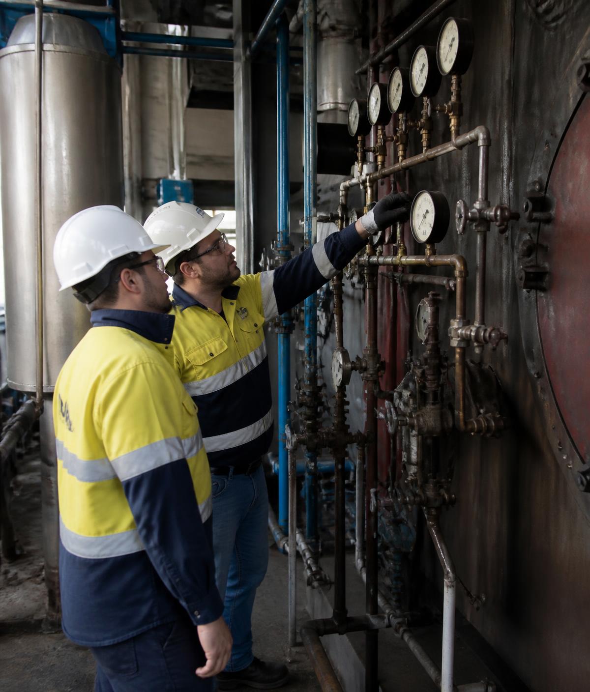 Two licensed operators inspecting boiler pressure gauges
